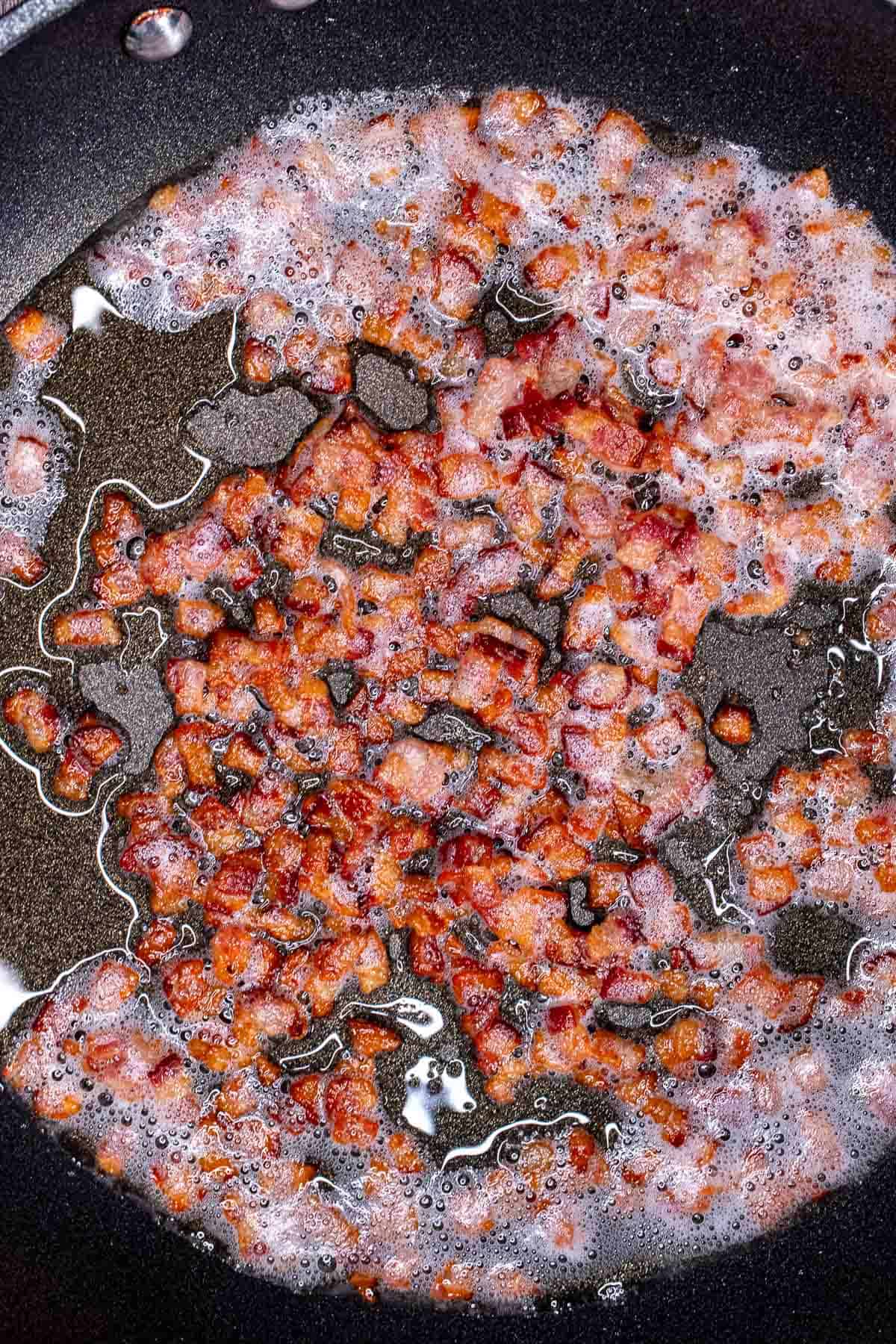 Diced bacon cooked in a skillet.