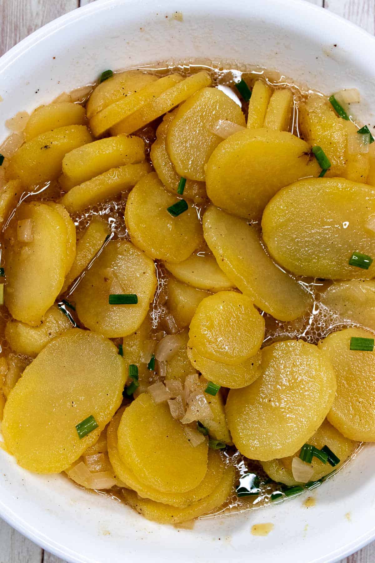 Marinated potatoes for Swabian potato salad tossed with oil and chives.