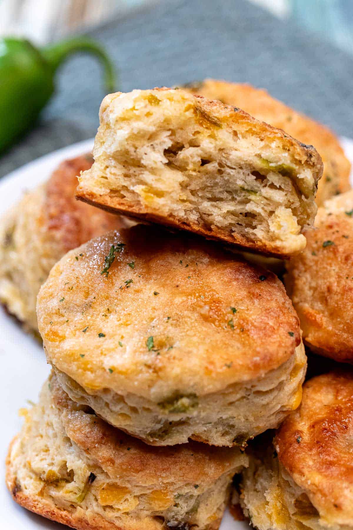 Hatch chile cheddar biscuits stacked on a plate with the top one bitten into.