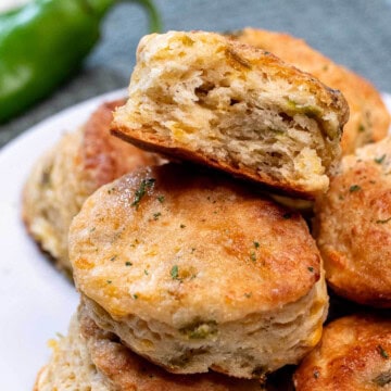 A plate of Hatch green chile cheddar biscuits with a bite taken out of one on top.