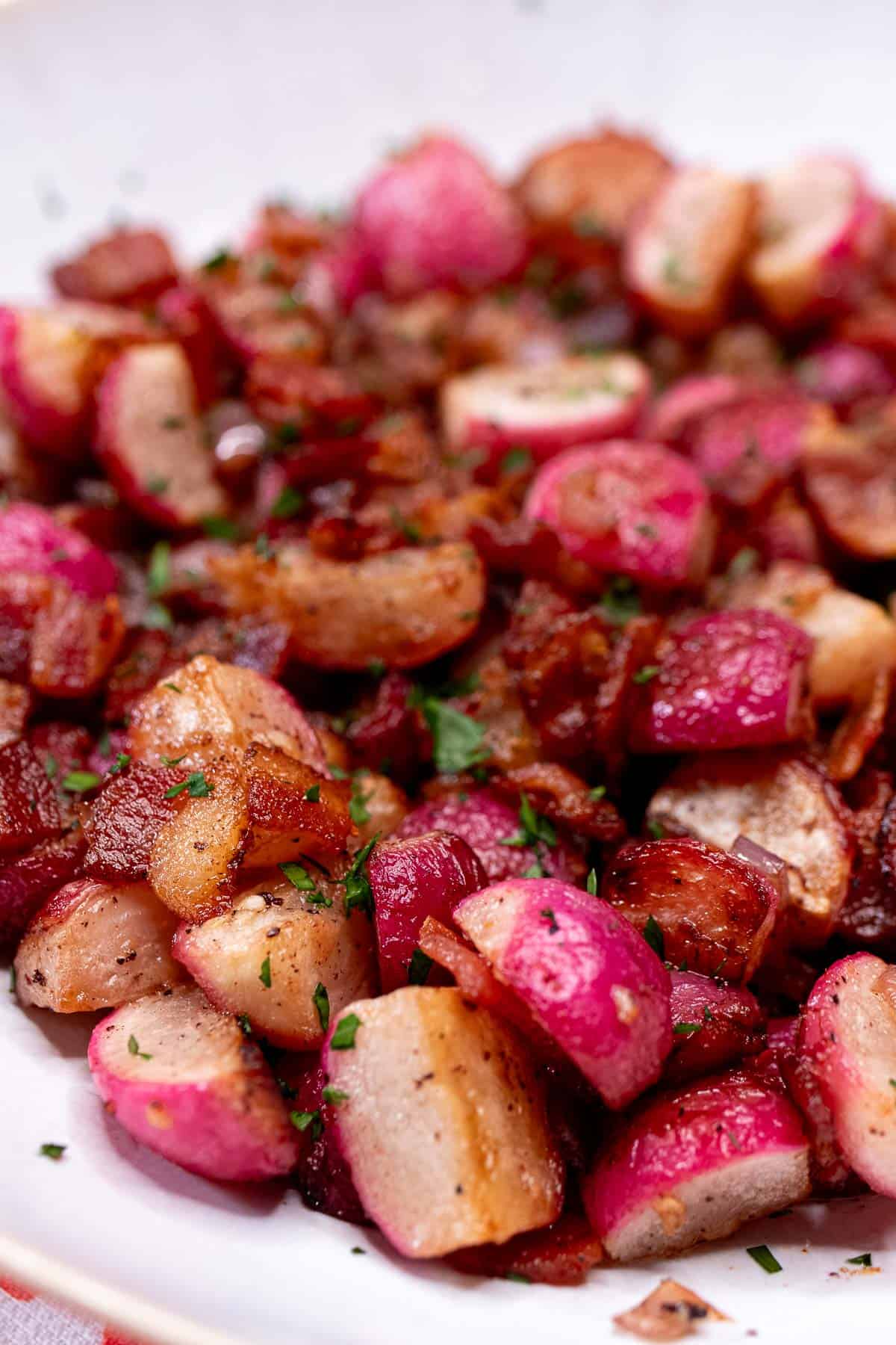 A bowl of sauteed radishes with bacon bits and shallot.