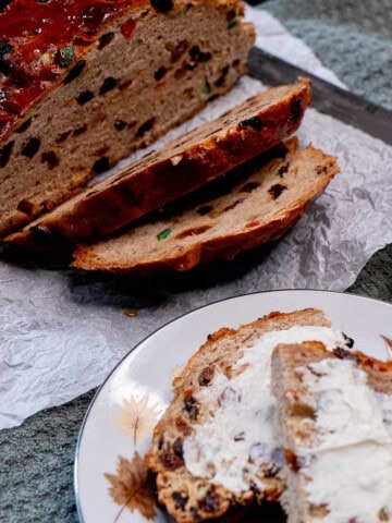 A sliced loaf of Irish barmbrack with some toasted and buttered slices on a plate.