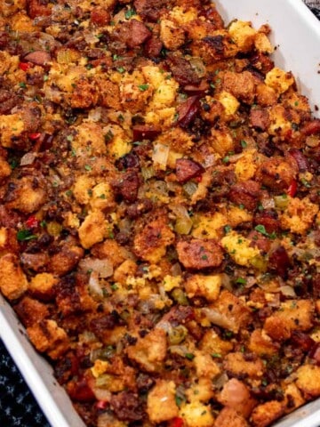 A large baking dish filled with Cajun sausage and mixed bread stuffing.