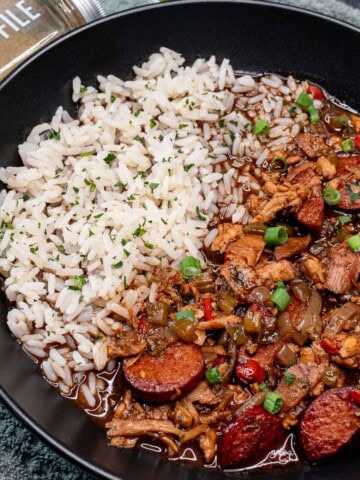 A large bowl of leftover turkey gumbo served with white rice and gumbo file.