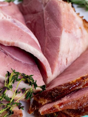 A maple bourbon glazed ham sliced onto a serving platter.