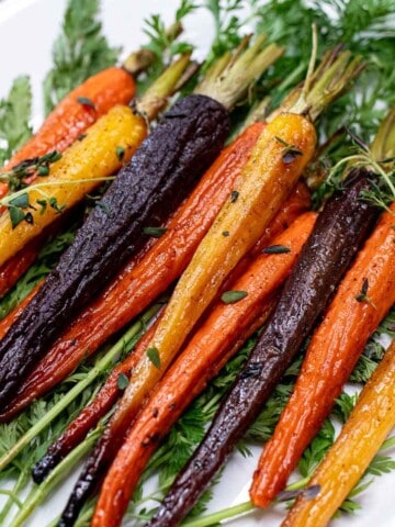 Maple roasted heirloom carrots on a serving plate topped with thyme.