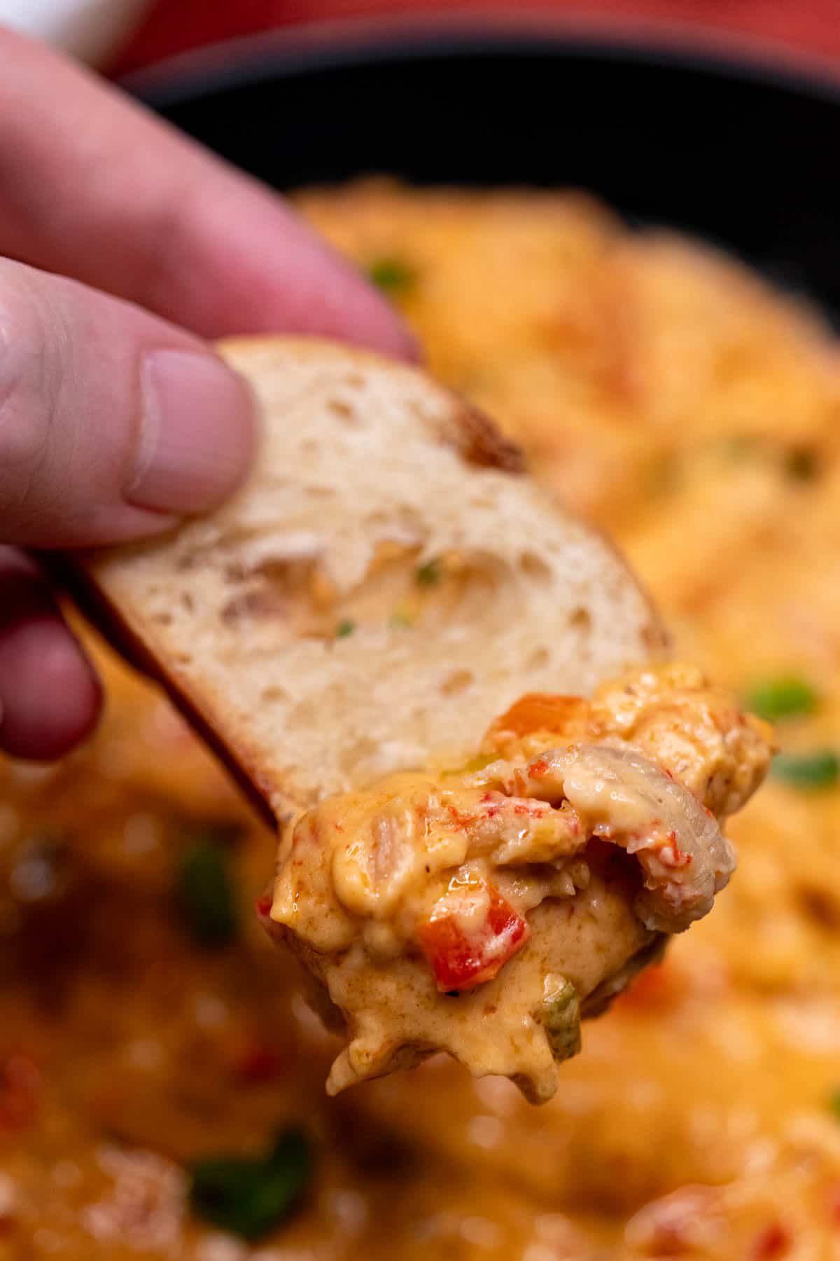 Dipping toasted French bread into a hot crawfish dip.