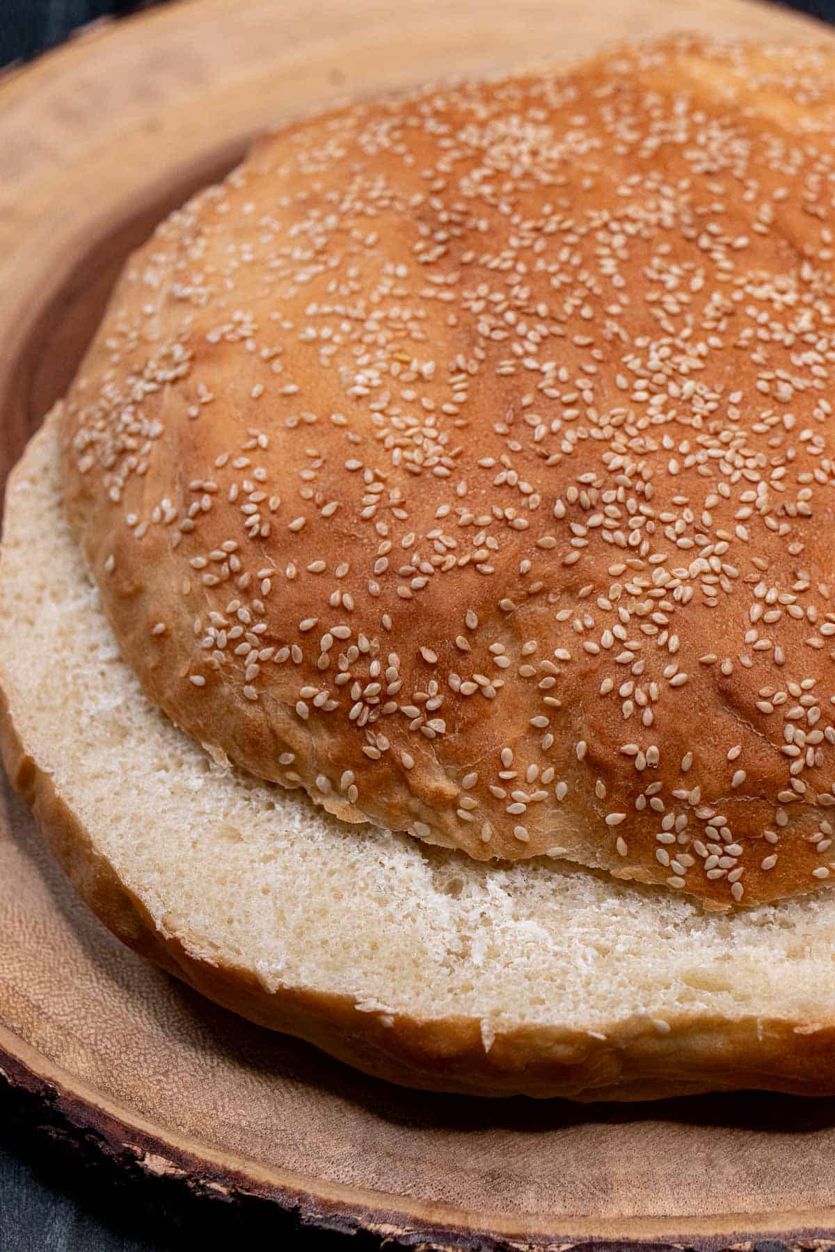 A large, round homemade muffaletta loaf sliced in half horizontally.