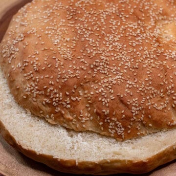 A large, round homemade muffaletta loaf sliced in half horizontally.