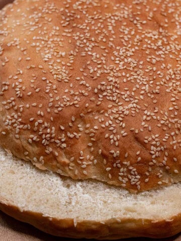 A large, round homemade muffaletta loaf sliced in half horizontally.