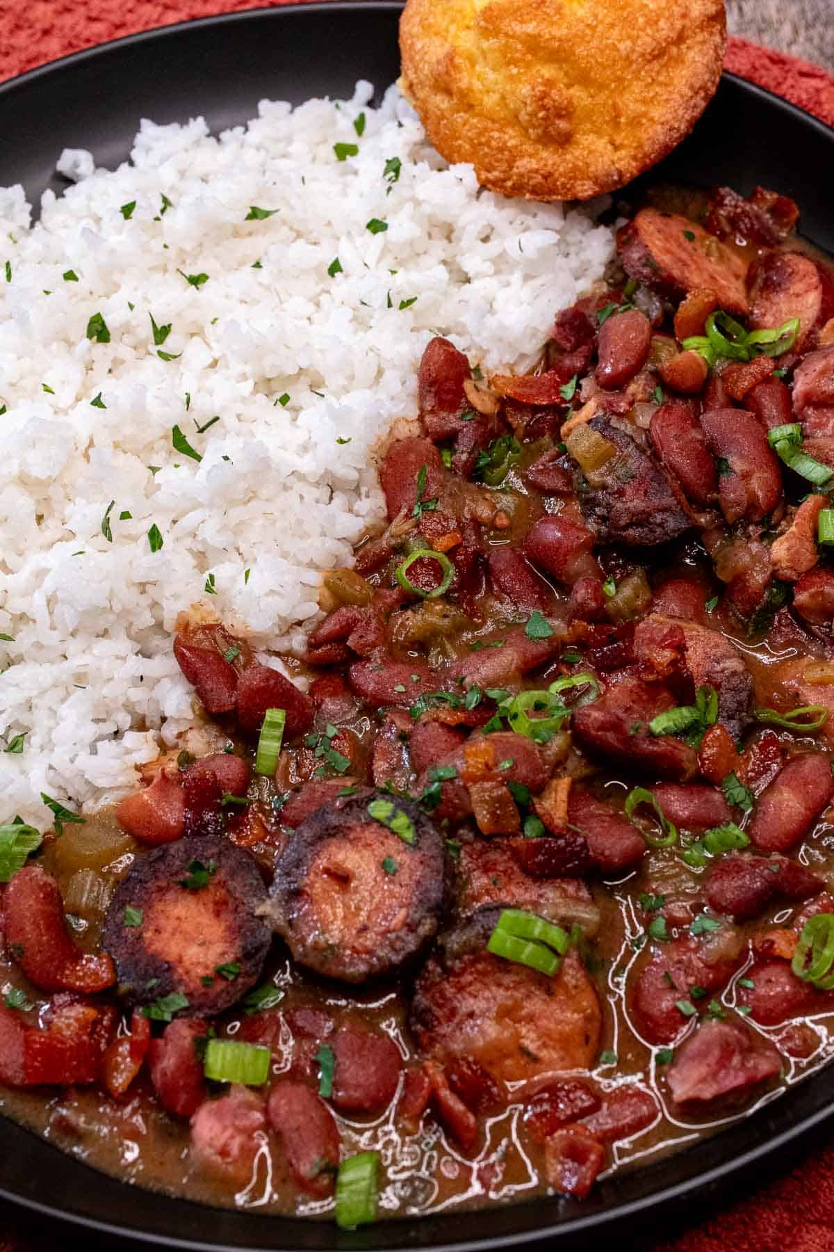 A plate of Creole red beans and rice with pork, served with white rice and cornbread.
