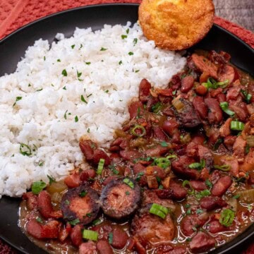 A plate of Louisiana red beans and rice with pork, served with white rice and cornbread.