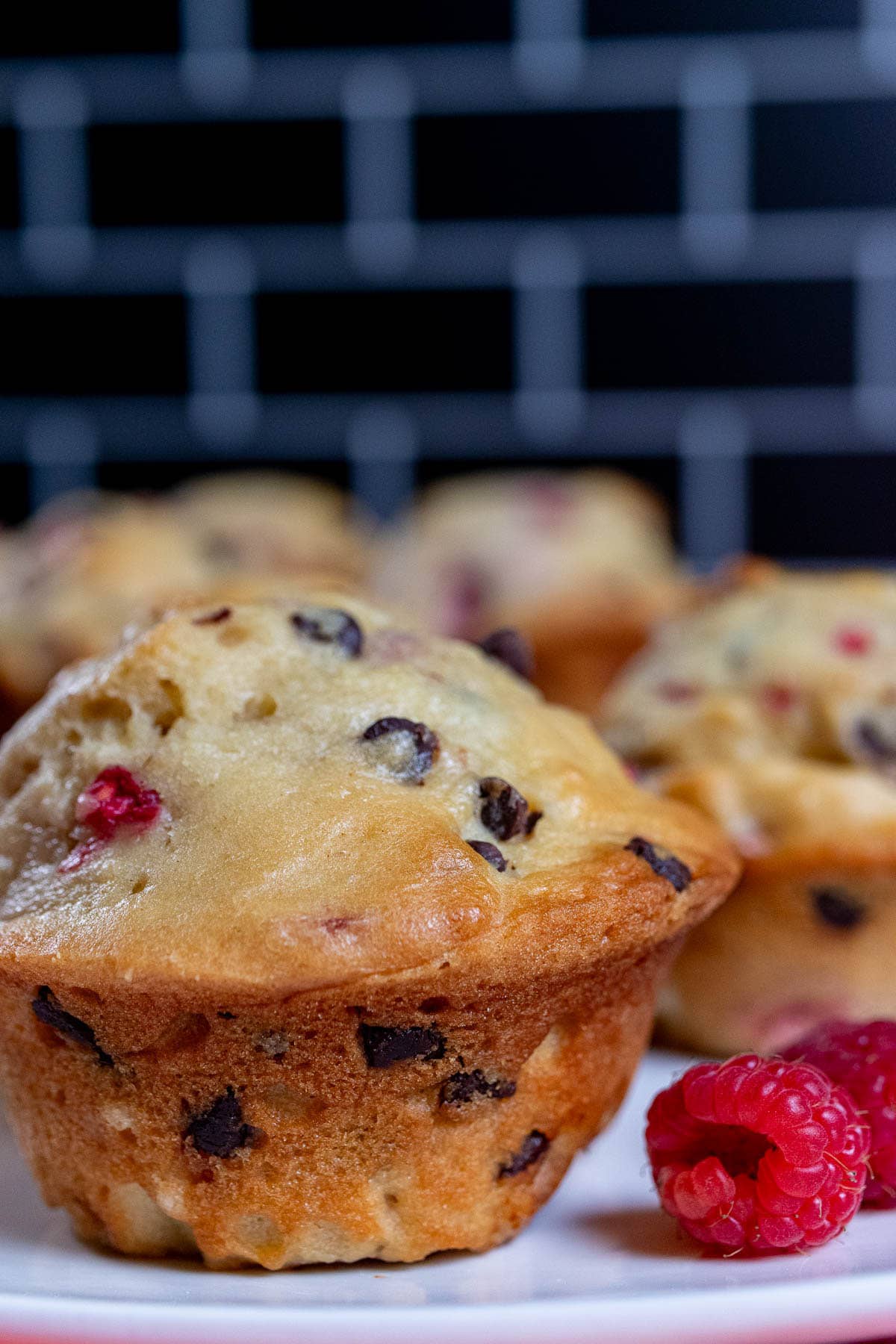 A bakery style chocolate raspberry muffin with some fresh raspberries next to it.