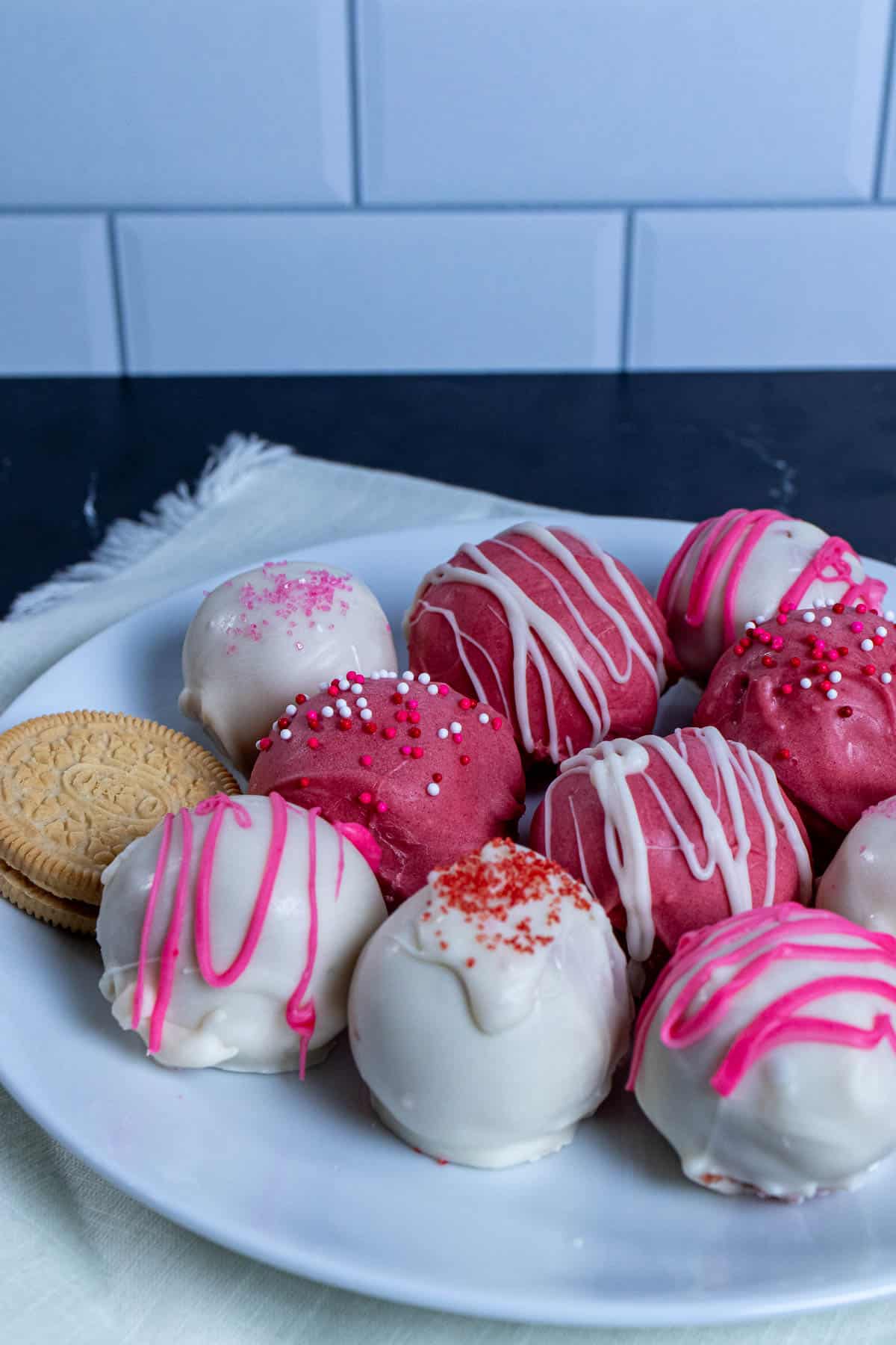 A plate filled with differently decorated strawberry shortcake truffles.