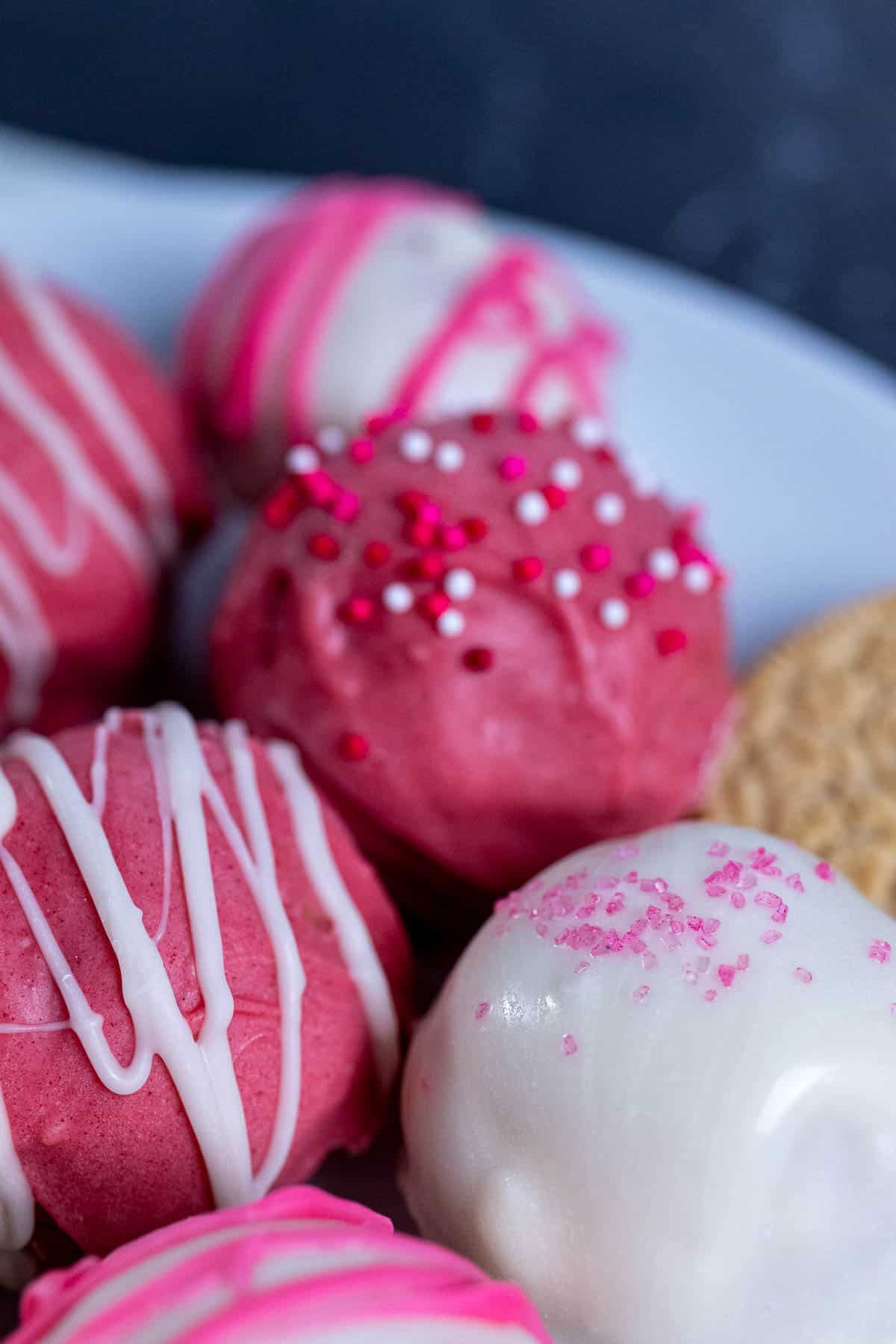 A plate of differently decorated strawberry cheesecake Oreo balls.