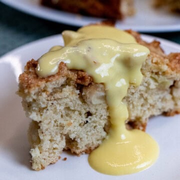 A slice of Irish apple cake topped with vanilla custard sauce.