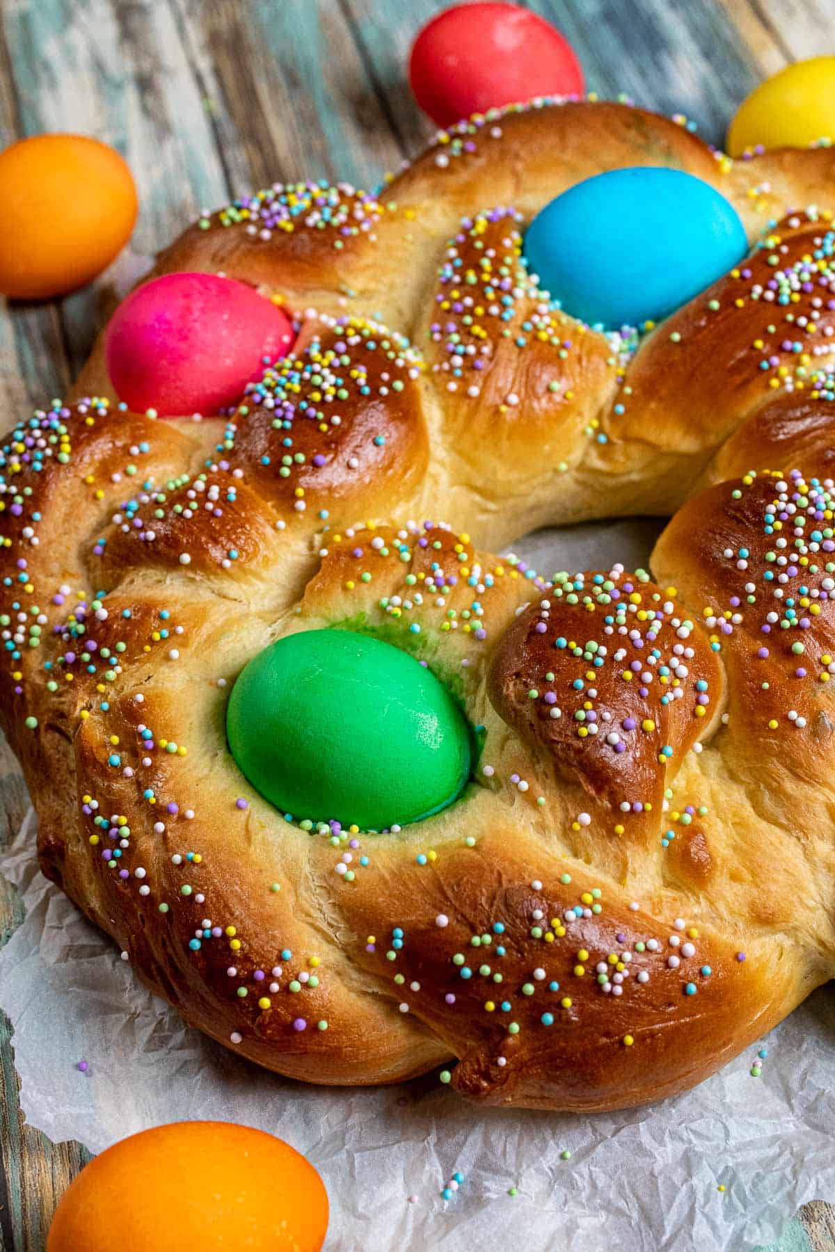 Italian Easter bread in a braided wreath and decorated with dyed eggs and sprinkles.