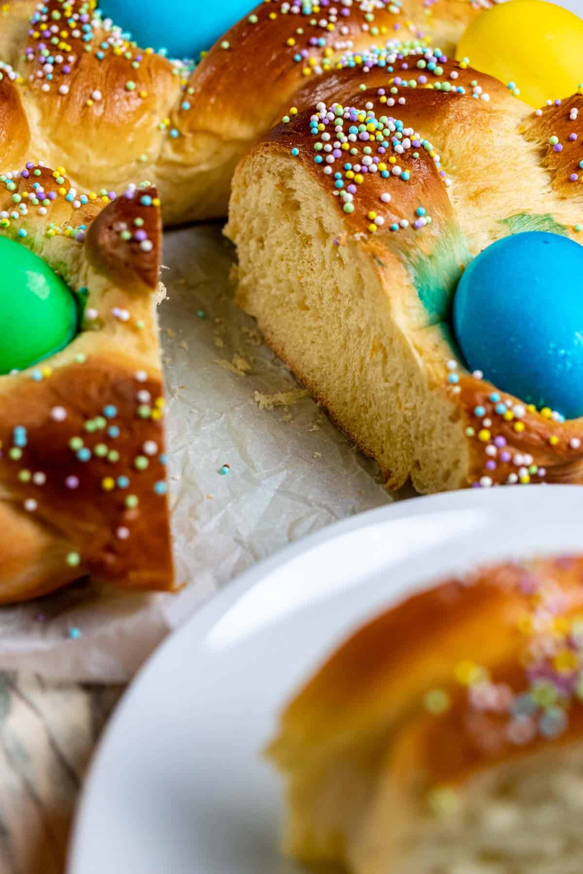 A sliced into braided loaf of Italian Easter bread with a slice out of focus in the foreground.