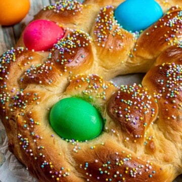 Italian Easter bread braided and shaped into a wreath, decorated with colored eggs and pastel sprinkles.