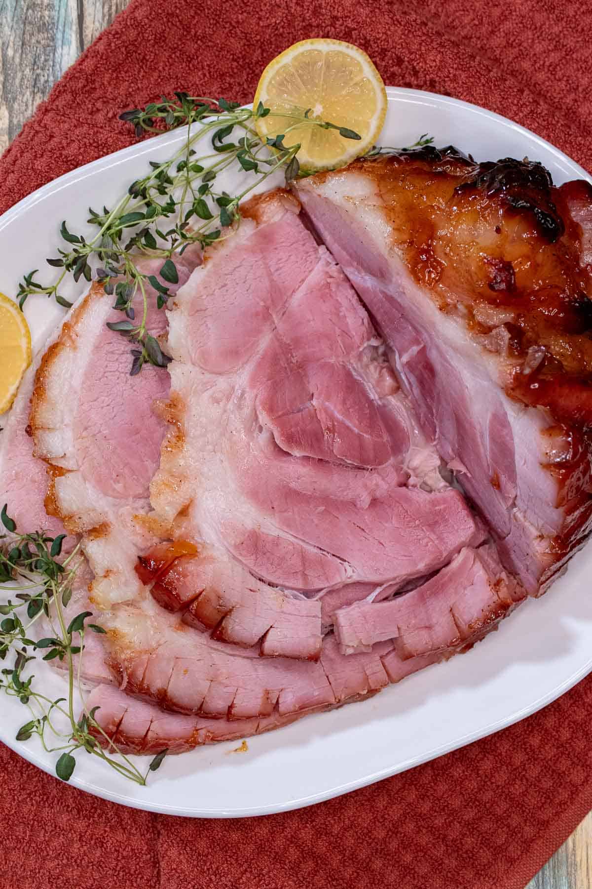 A peach and bourbon glazed ham carved on a serving platter.