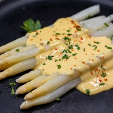 German white asparagus topped with hollandaise sauce and fresh parsley.