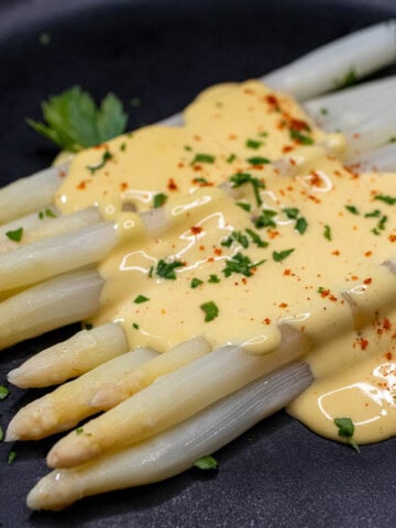 German white asparagus topped with hollandaise sauce and fresh parsley.
