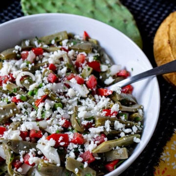 Mexican cactus salad in a serving bowl, topped with crumbled queso fresco.