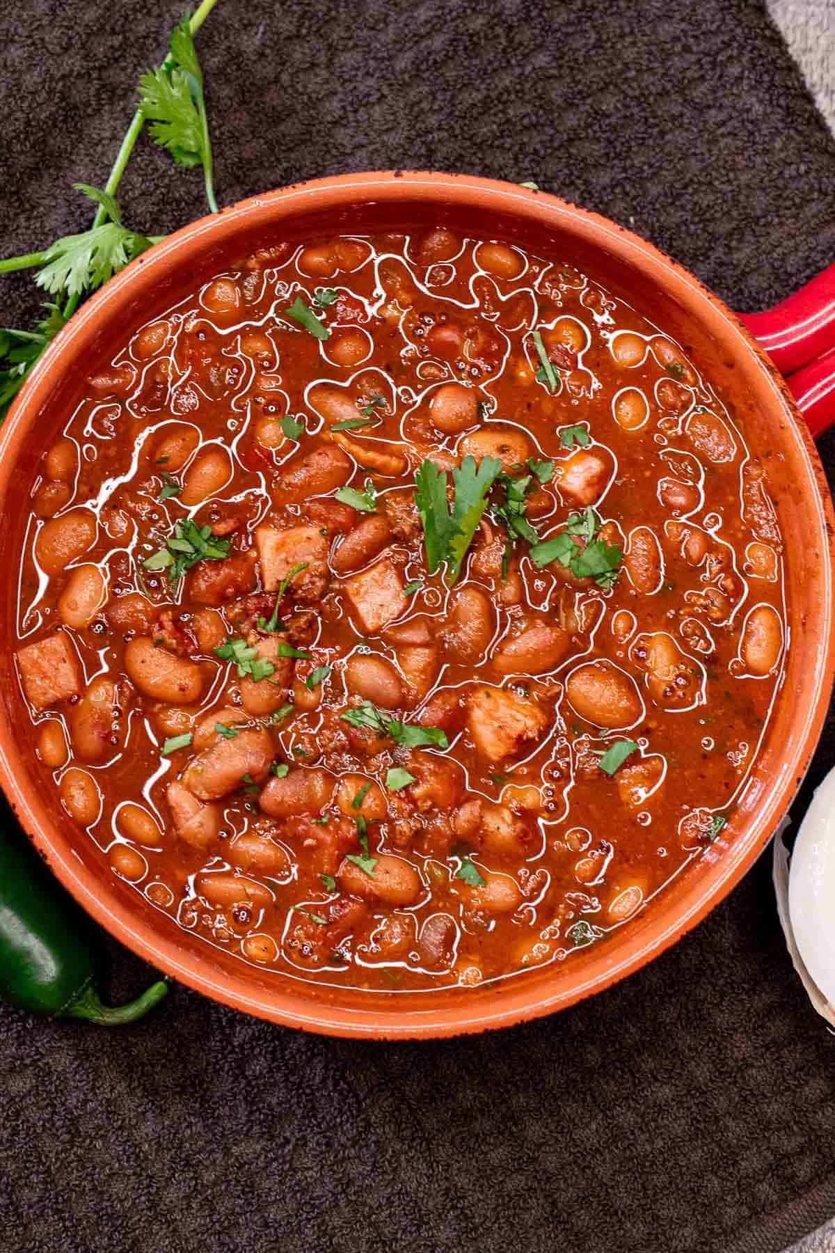 A bowl of charro beans with fresh cilantro sprinkled on top.