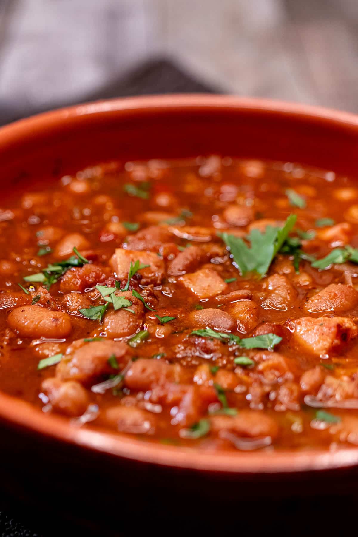 Close view of charro beans with ham, bacon, and chorizo inside.