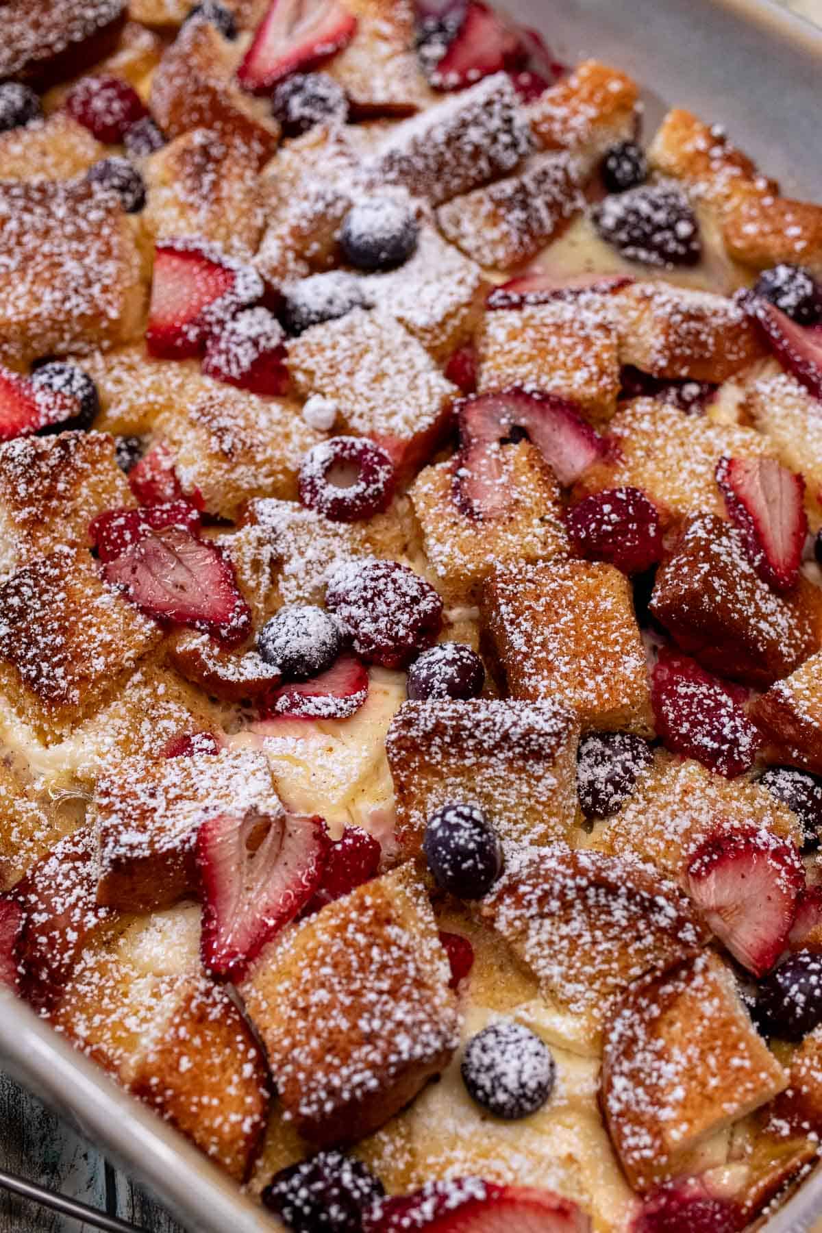 Mixed berries and cream French toast casserole topped with powdered sugar.