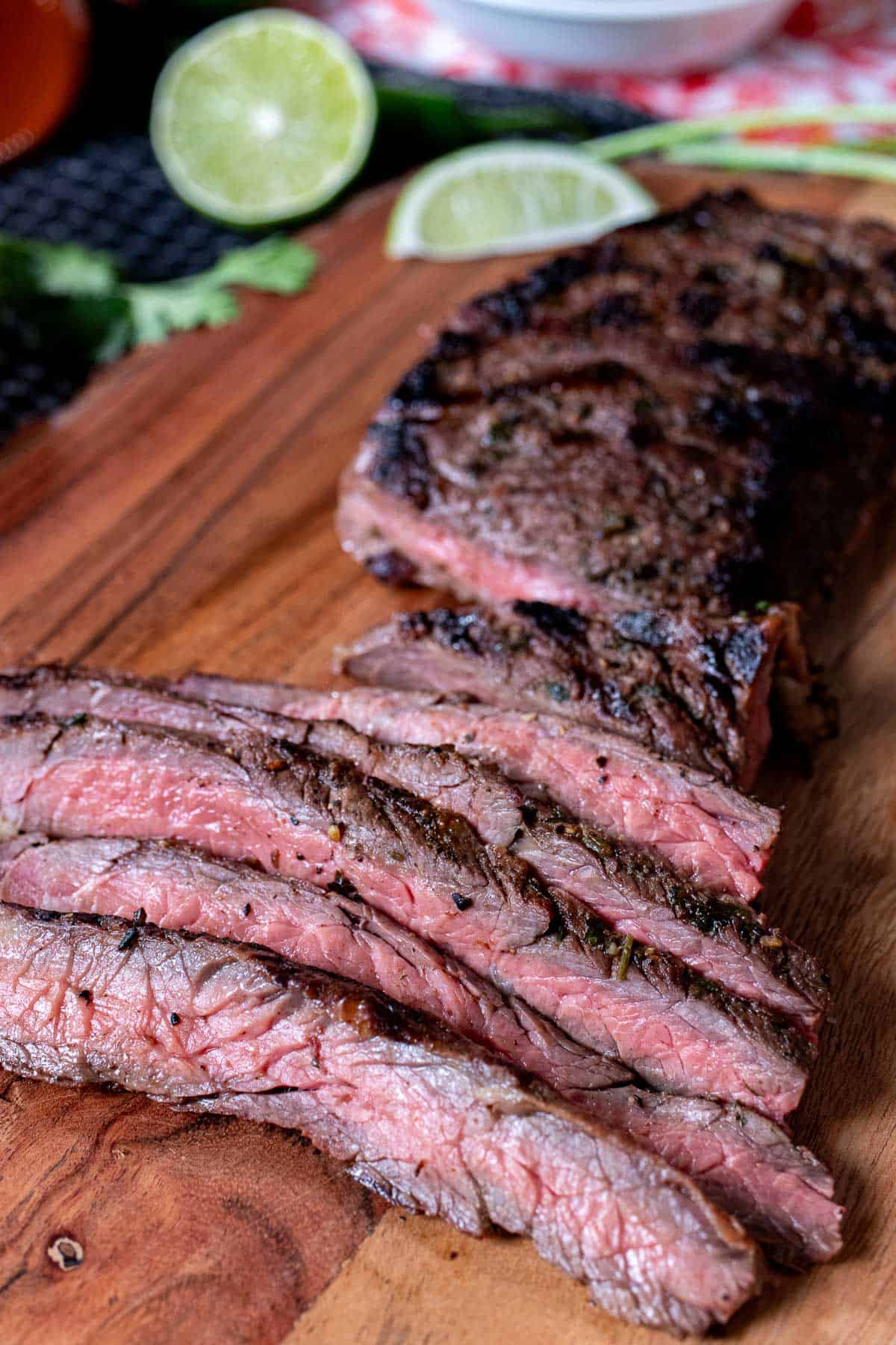 Carne asada skirt steak sliced thinly across the grain and displayed on a wooden board.