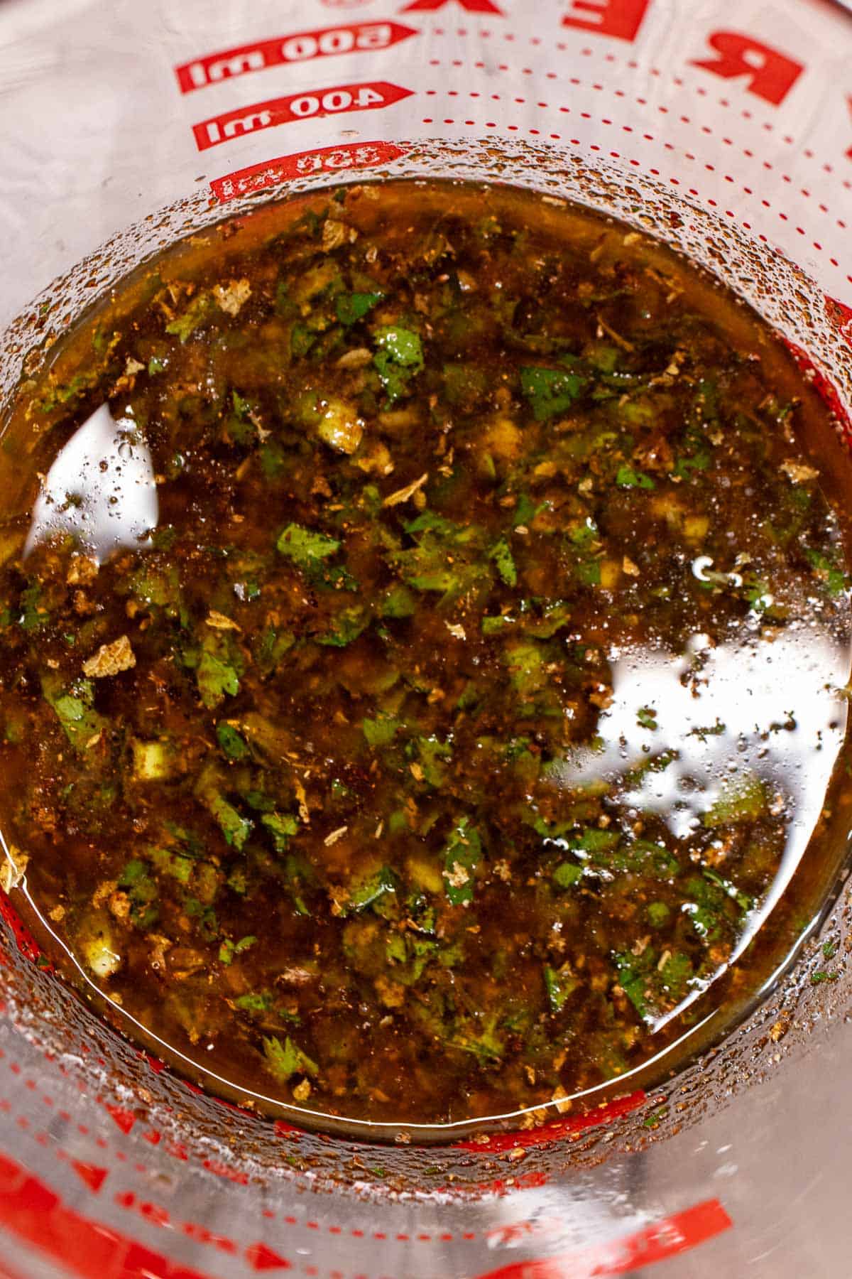 Carne asada marinade mixed in a glass measuring cup.