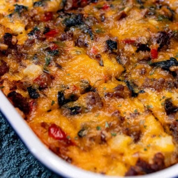 A baking dish full of sausage and egg breakfast casserole with portions cut and ready for serving.