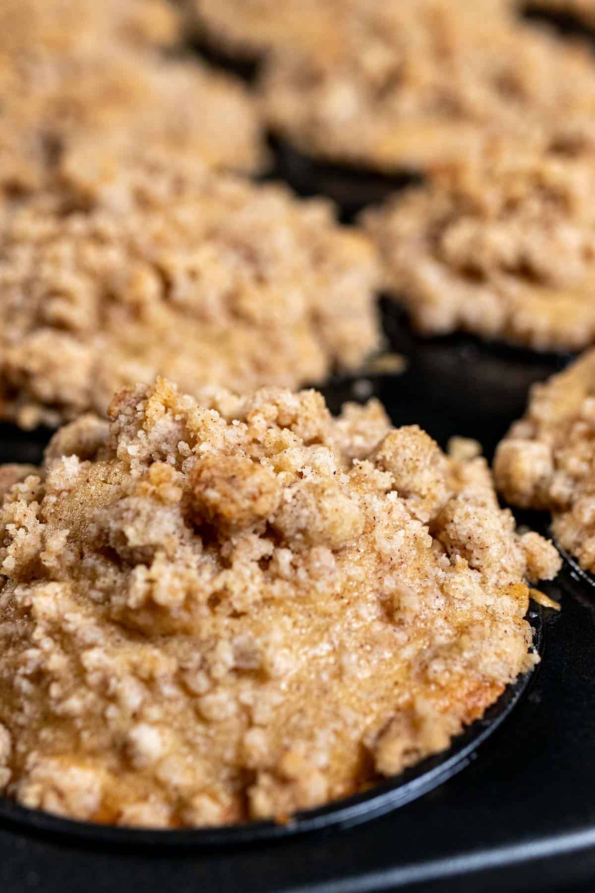 Apple cider muffins with crumble topping in muffin pan.