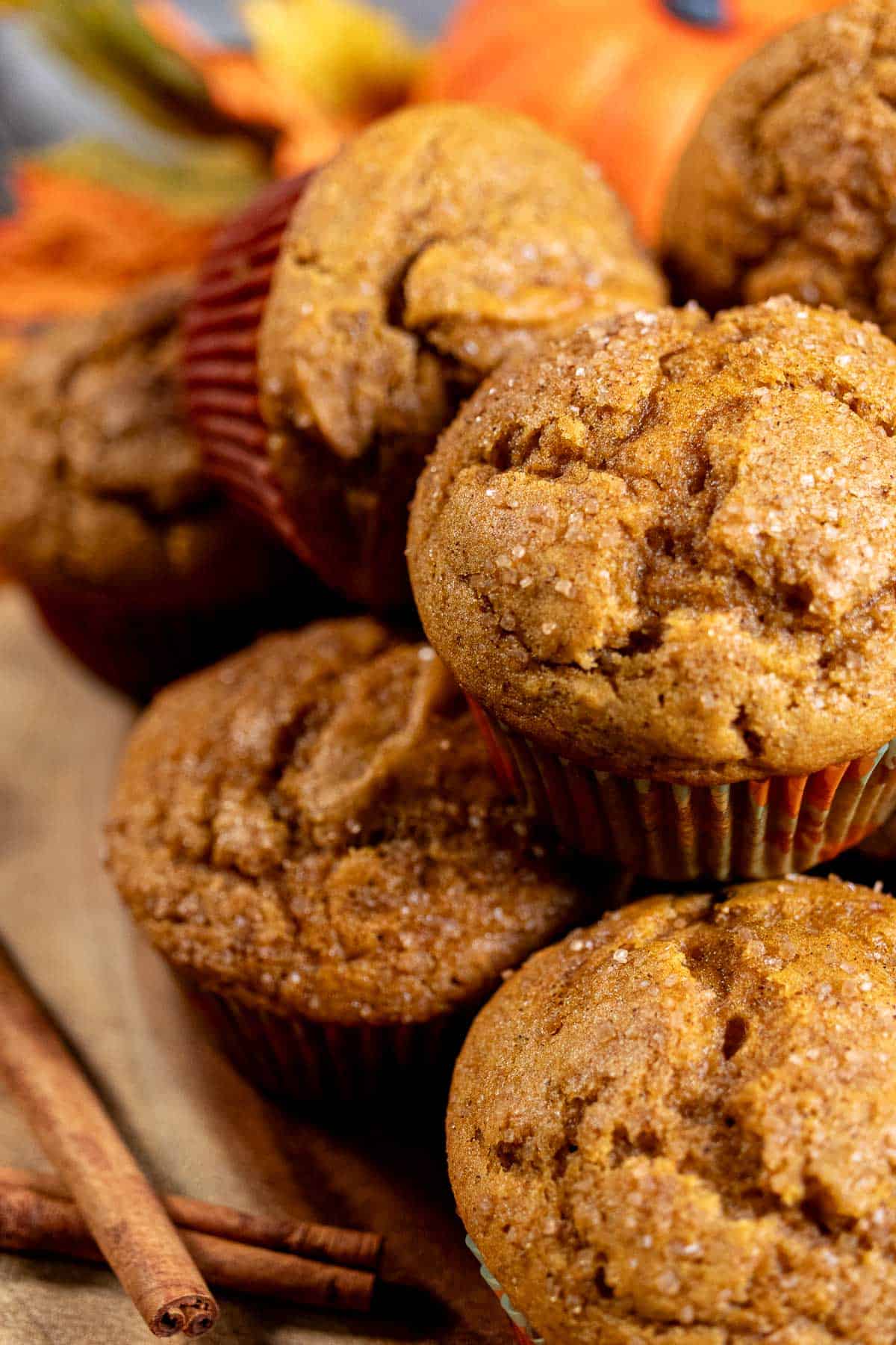 A stack of pumpkin spice muffins with a cinnamon stick next to them.