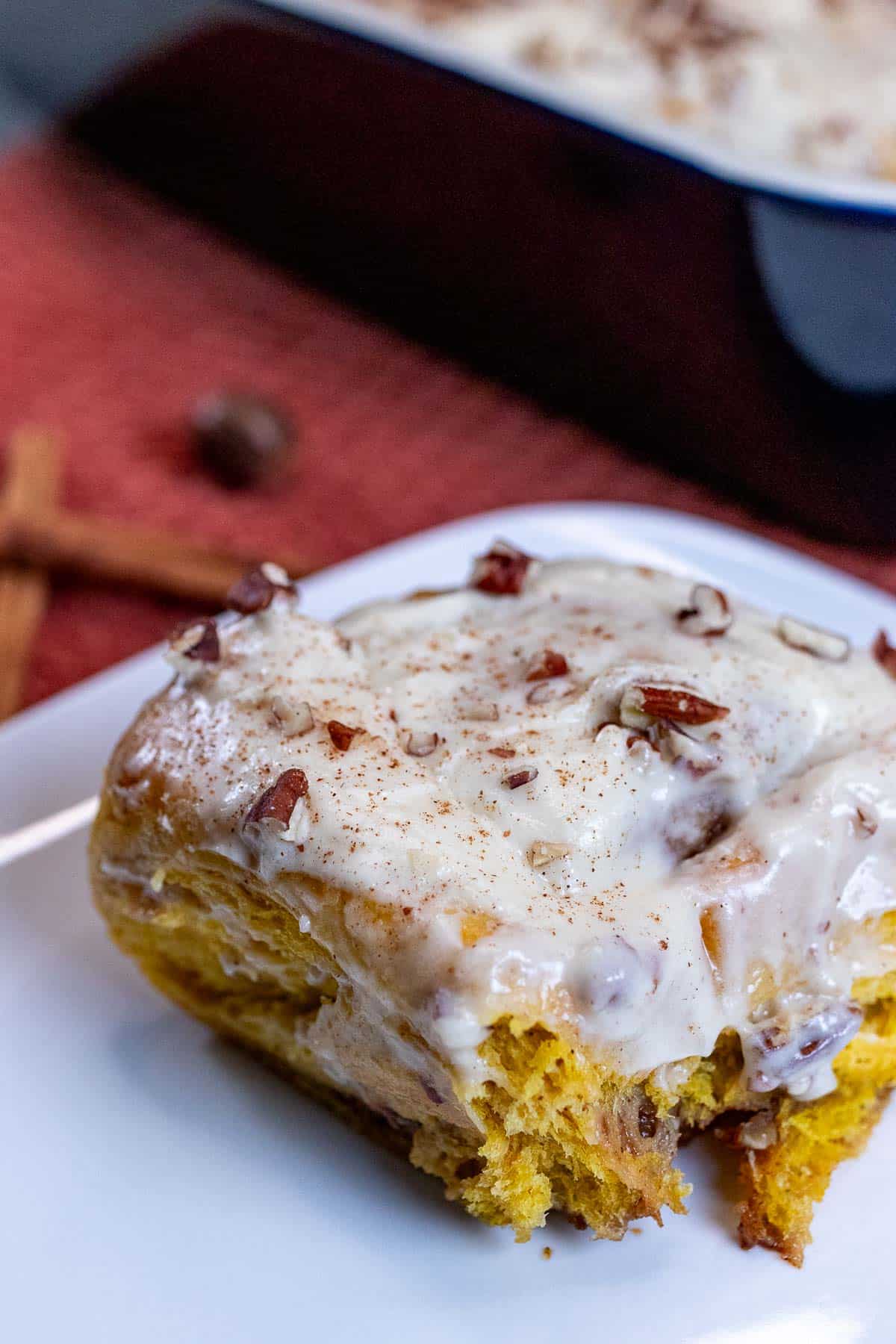Pumpkin pecan cinnamon roll on a white plate.