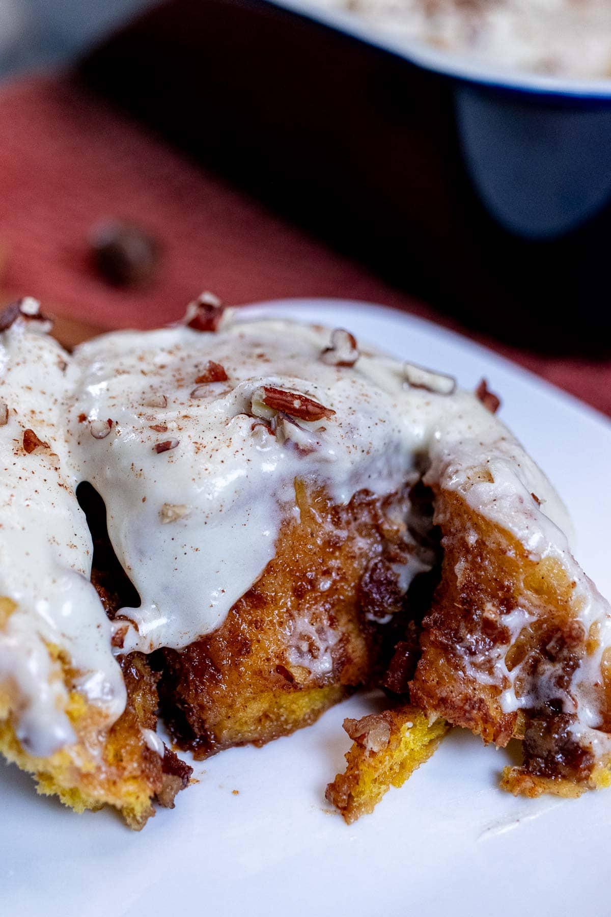 A pumpkin pecan cinnamon roll torn open on a plate.