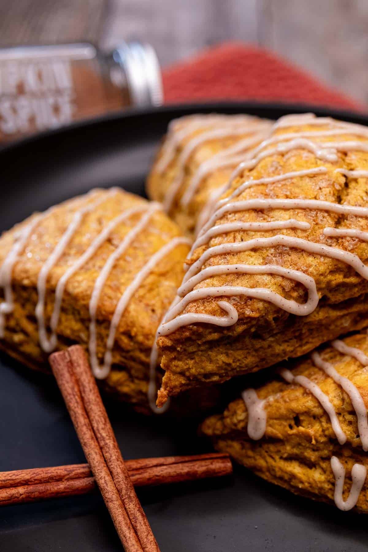 A plate of pumpkin scones with maple cinnamon glaze drizzled over top of them.